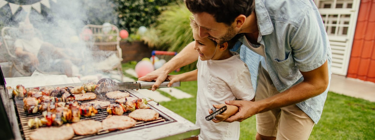 Ein Vater grillt gemeinsam mit seinem kleinen Sohn