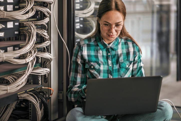 Fachinformatikerin Azubi sitzt vor Serverschrank