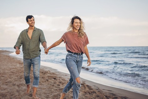 Ein Paar spaziert freudig an der Ostsee bei ihrer Gesundheitsreise.