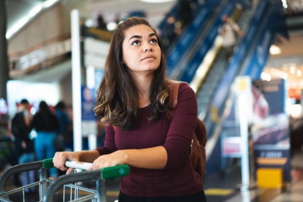 Eine junge Frau mit Flugangst studiert die Abflugstafel im Terminal