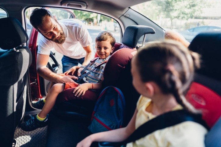 Ein Familienvater sichert seine Kinder für eine Autoreise