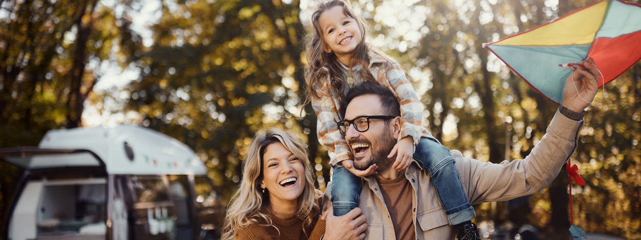 Eine junge Familie macht einen Herbstausflug mit einem Drachen in der Natur.