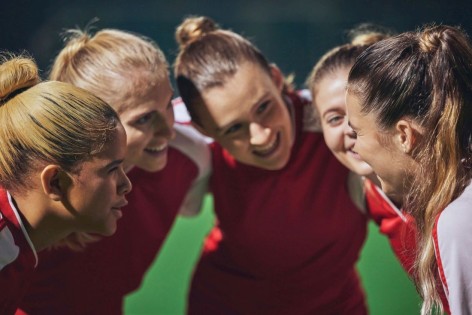 Eine Frauensportgruppe steckt die Köpfe zusammen.