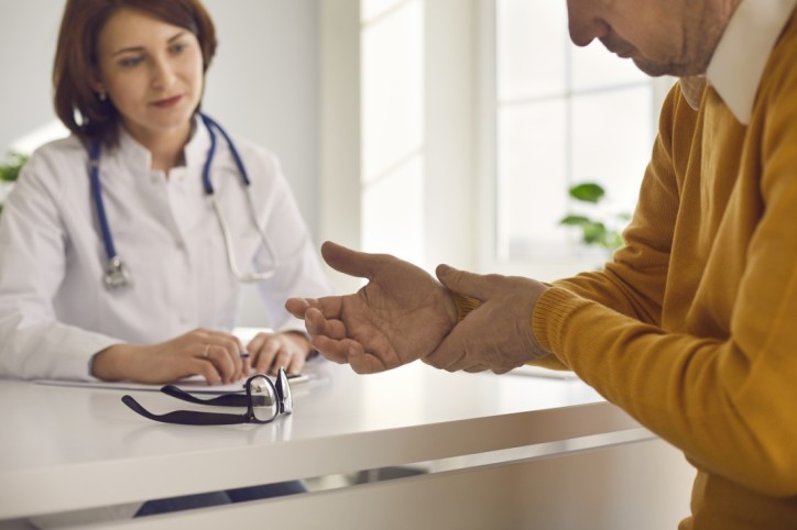 Ärztin begutachtet Handgelenk eines Patienten mit Verdacht auf Rheuma.