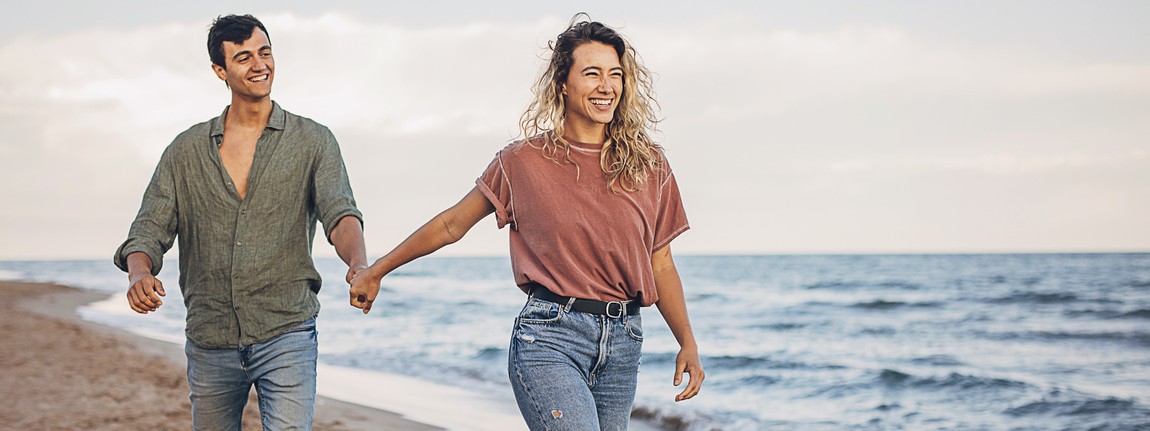 Ein Paar spaziert freudig an der Ostsee bei ihrer Gesundheitsreise.