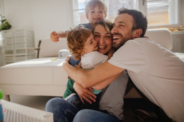 Junge Familie beim Spielen mit ihren Kindern im Wohnzimmer.