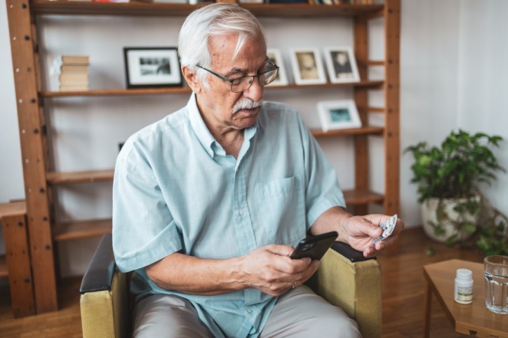 Ein Senior überprüft ein Medikament seiner Reiseapotheke