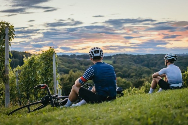 Zwei Fahrradfahrer machen rast an einem Weinberg am Saale-Radweg.