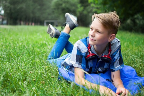 Junge liegt auf Wiese und schaut hoffnungsvoll