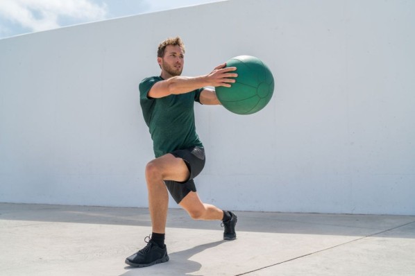 Ein Mann trainiert mit einem Wallball für HYROX