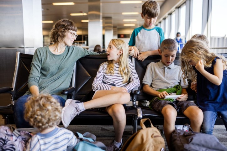 Eine Mutter sitzt mit ihren Kindern und Gepäck am Flughafen und wartet