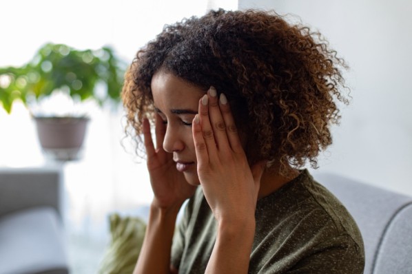 Eine 30-jährige Frau leidet unter Misophonie und fässt sich an die Schläfen.