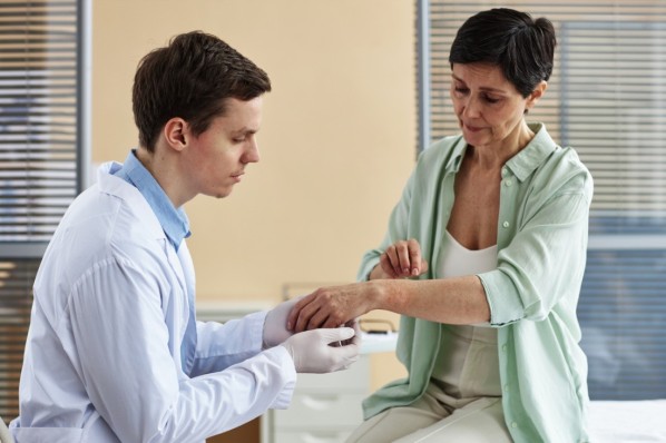 Ein Arzt untersucht den Arm einer Patientin mit Skabies-Verdacht