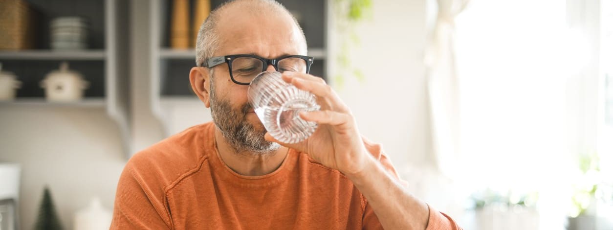 Ein Mann genießt ein Glas Wasser mit Kohlensäure