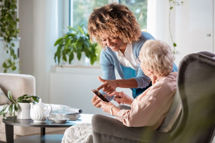 Eine Pflegerin zeigt einer Seniorin eine digitale Pflegeanwendung